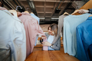Young stylist looking through set of shirts for fashion shooting