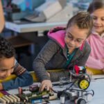 Group of small kids working on motherboard and robots in laboratory.
