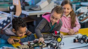 Group of small kids working on motherboard and robots in laboratory.